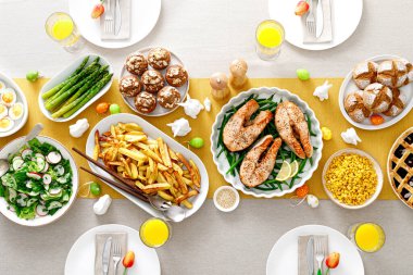Somon, kuşkonmaz, salata, patates, kek ve böğürtlenli Paskalya bayramı masası.