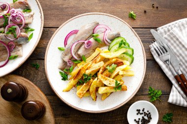 Soğanlı salamura fileto ve tabakta kızarmış patates.