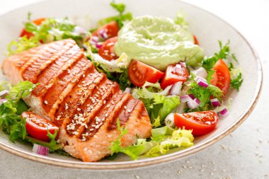 Izgara somon balığı fileto ve taze yeşil marul sebzeli domates salatası avokado guacamole