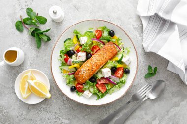 Somon balığı salatası. Taze sebze salatası, domates, biber, marul, zeytin, salatalık, feta peyniri ve ızgara somon balığı filetosu kasede sağlıklı yemek, omega 3, keto diyeti, Akdeniz sümüğü, üst görüş..