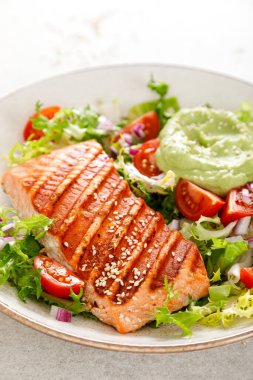 Izgara somon balığı fileto ve taze yeşil marul sebzeli domates salatası avokado guacamole
