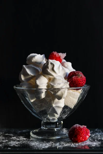 玻璃碗加糖蛋白 玻璃桌上放着冰冻草莓 在阳光下 在黑暗的背景下 — 图库照片