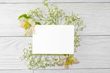 Hafif ahşap arka planda pembe gül yaprakları ve küçük beyaz çiçekler deseni. Güzel bir yaz, bahar gazetesi kartpostallar ve tasarım için arka plan oluşturur..