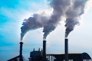 Endüstriyel fabrikadan yükselen duman parlak güneşle gökyüzüne yükseliyor 