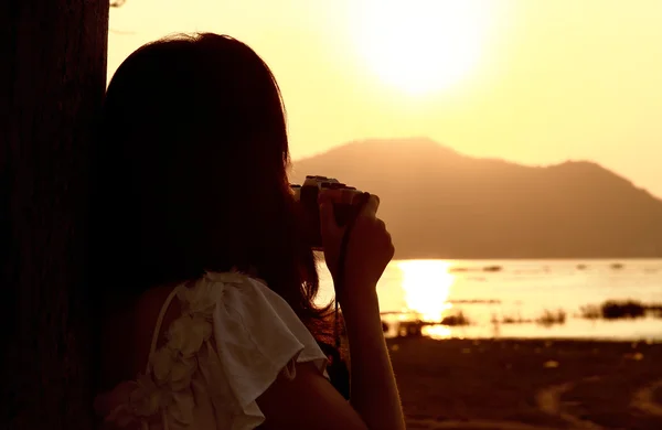 Gün Batımında Kıyıda Oturan Fotoğraf Çeken Genç Bir Kadının Silueti — Stok fotoğraf