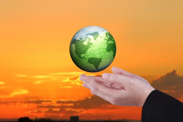 female human hands holding float green global over industrial factory sunset background for green concept