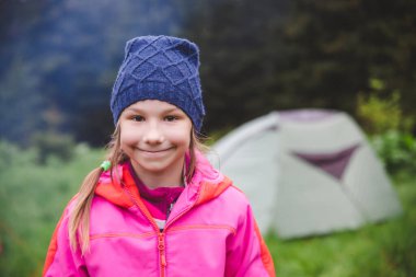 Karpat dağlarında çadırın yanında poz veren küçük turist kız.