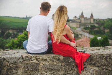 Ukrayna 'daki Kamianets-Podilskyi Kalesi' nin önünde oturan genç çift.
