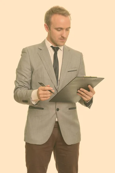 Bonito homem de negócios caucasiano escrevendo relatório na área de transferência — Fotografia de Stock