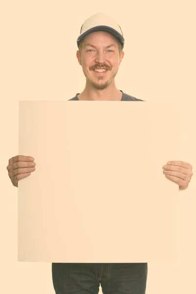 Portrait de heureux jeune homme barbu beau tenant tableau blanc — Photo