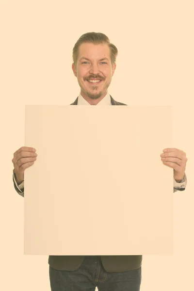 Portrait de jeune homme d'affaires barbu heureux tenant tableau blanc — Photo