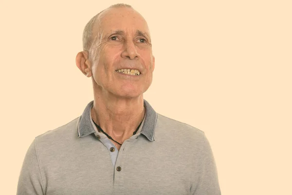 Studio shot of happy senior man smiling while thinking — Stock Photo, Image