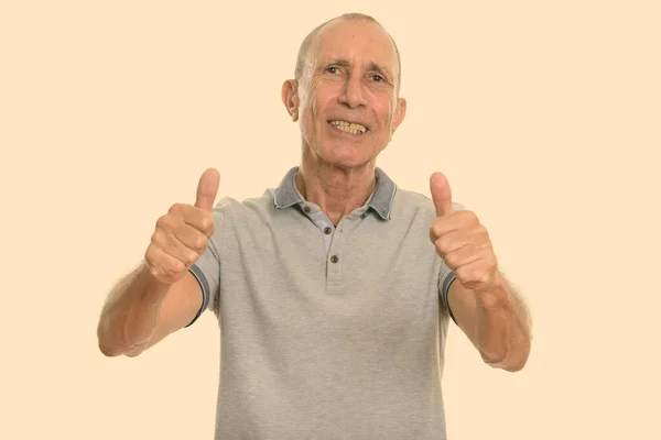 Estúdio tiro de homem sênior feliz sorrindo e dando polegares para cima — Fotografia de Stock