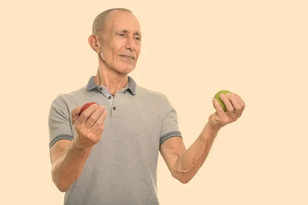 Studio colpo di felice uomo anziano sorridente e in possesso di mela rossa, mentre guardando mela verde — Foto Stock