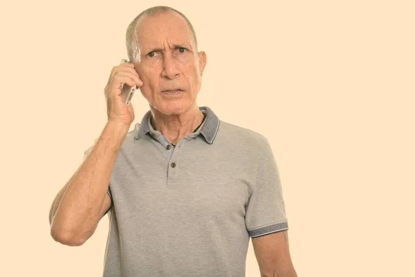 Студийный снимок злого пожилого человека, разговаривающего по мобильному телефону — стоковое фото