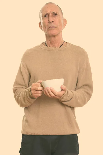 Studio shot di arrabbiato uomo anziano in possesso di tazza di caffè — Foto Stock