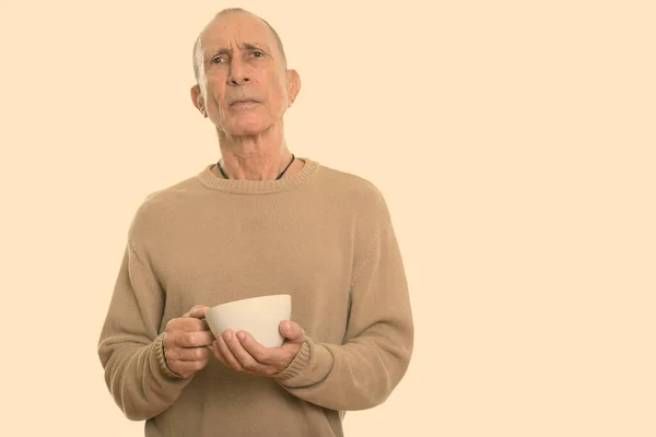 Студийный снимок злого пожилого мужчины с кофейной чашкой — стоковое фото