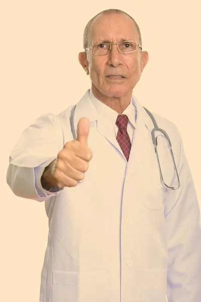 Студийный снимок старшего врача, показывающего большой палец — стоковое фото