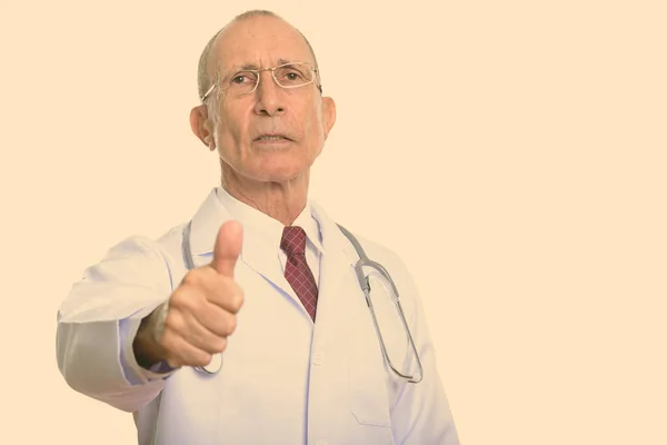 Studio shot of senior man doctor giving thumb up — Stock Photo, Image