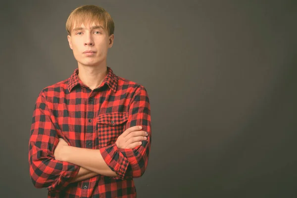 Jovem homem bonito com cabelo loiro contra fundo cinza — Fotografia de Stock