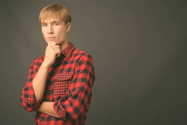 Jovem homem bonito com cabelo loiro contra fundo cinza — Fotografia de Stock