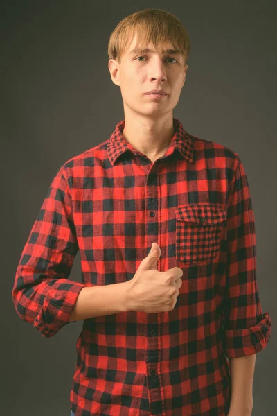 Junger schöner Mann mit blonden Haaren vor grauem Hintergrund — Stockfoto