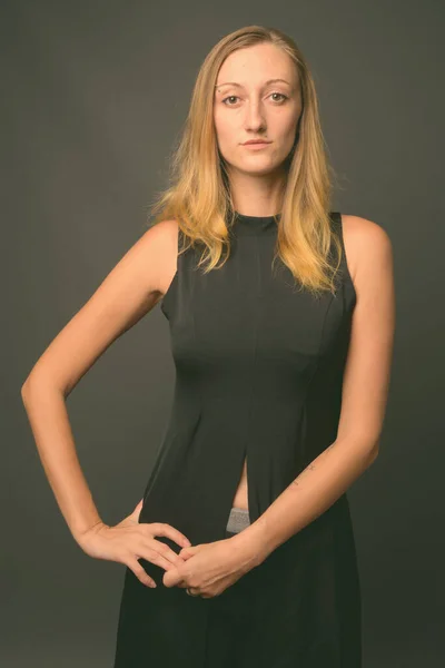 Junge schöne Geschäftsfrau mit glatten blonden Haaren vor grauem Hintergrund — Stockfoto