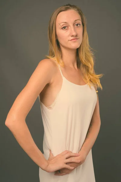 Junge schöne Frau mit glatten blonden Haaren vor grauem Hintergrund — Stockfoto
