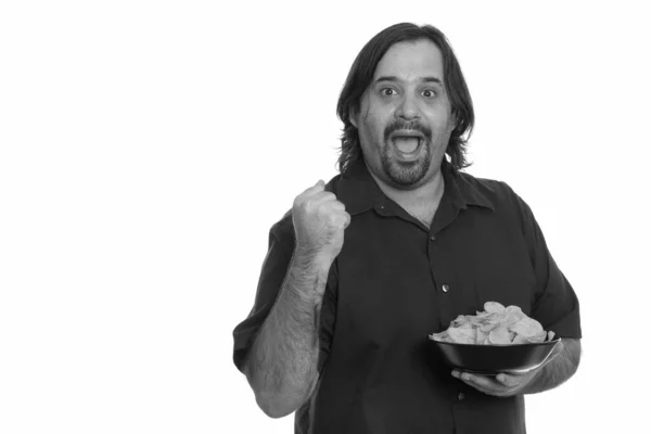 Happy fat Caucasian man smiling and looking motivated while holding bowl of chips — Stock Photo, Image