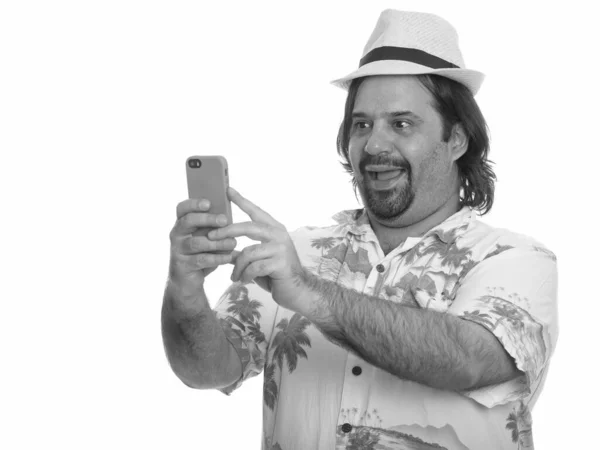 Щасливий товстий кавказький чоловік посміхається і бере себе в руки з мобільним телефоном, готовим до відпустки. — стокове фото