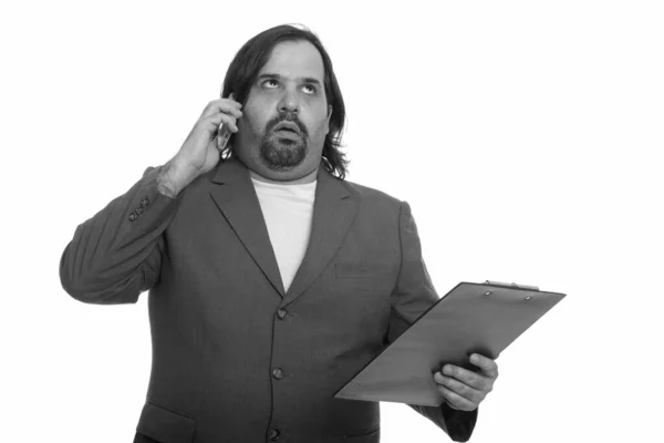Dicker kaukasischer Geschäftsmann sieht genervt aus, während er am Handy spricht und Klemmbrett hält — Stockfoto