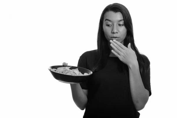 Молодая красивая белая женщина держит миску картофельных чипсов и покрывает рот — стоковое фото