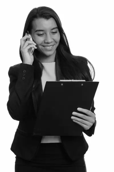 Giovane donna d'affari caucasica felice sorridente e parlando sul telefono cellulare durante la lettura negli appunti — Foto Stock