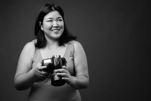 Linda mulher asiática com sobrepeso contra fundo cinza — Fotografia de Stock