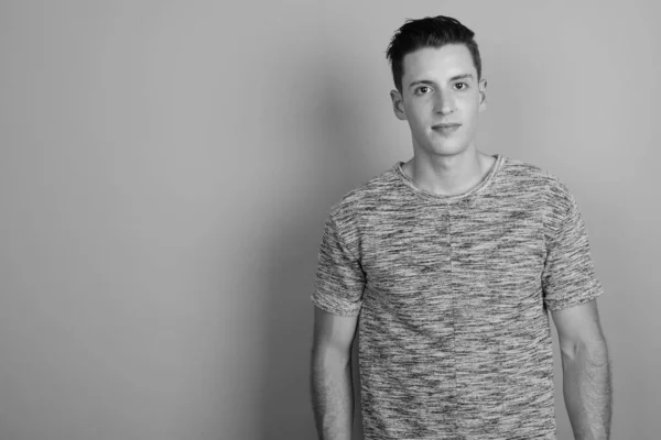 Young handsome man wearing gray shirt against gray background — Stock Photo, Image