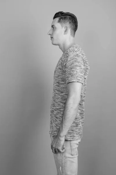 Jovem homem bonito vestindo camisa cinza contra fundo cinza — Fotografia de Stock