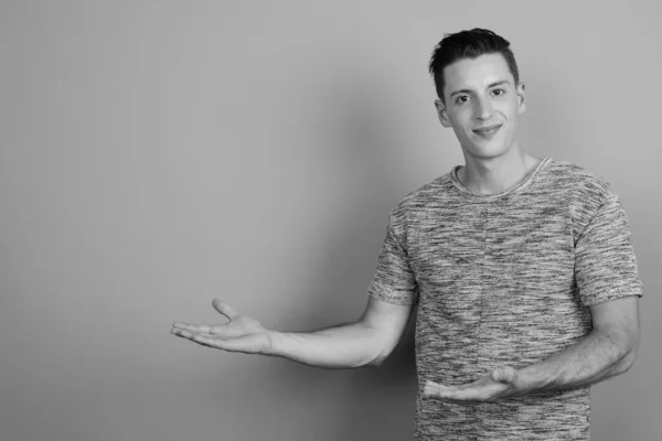 Young handsome man wearing gray shirt against gray background — Stock Photo, Image