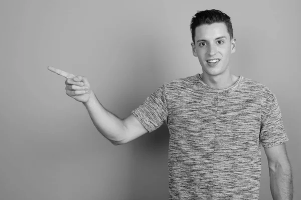 Joven hombre guapo con camisa gris sobre fondo gris — Foto de Stock