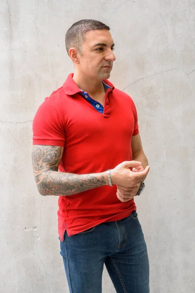 Красивий чоловік з татуюваннями, думаючи про бетонну стіну — стокове фото