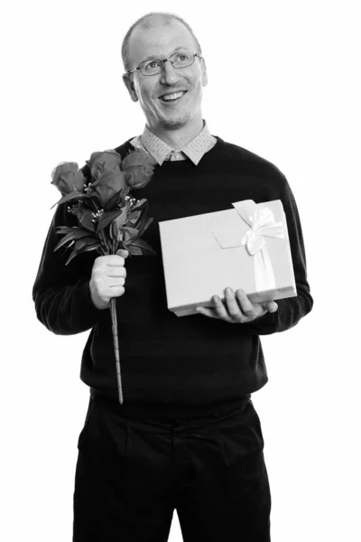 Pensativo hombre feliz sonriendo mientras sostiene rosas y caja de regalo listo para el día de San Valentín —  Fotos de Stock