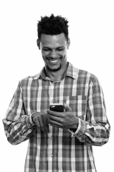工作室拍摄的年轻快乐的非洲男人一边笑一边用手机 — 图库照片