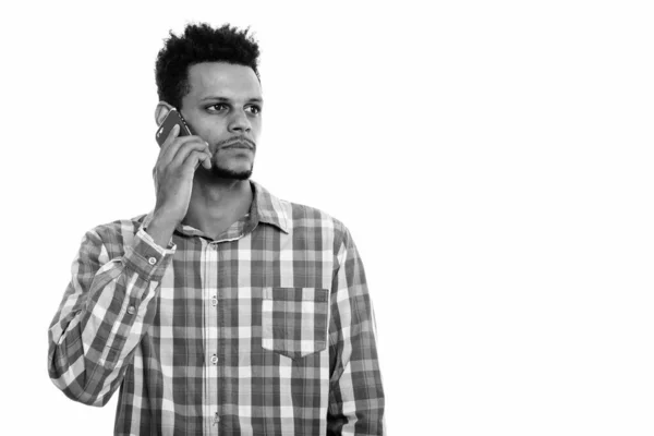 携帯電話で話している若いアフリカ人男性のスタジオショットを考えながら — ストック写真