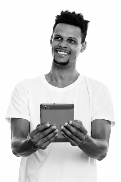 有思想的年轻快乐的非洲人一边微笑，一边用双手拿着数码平板电脑 — 图库照片
