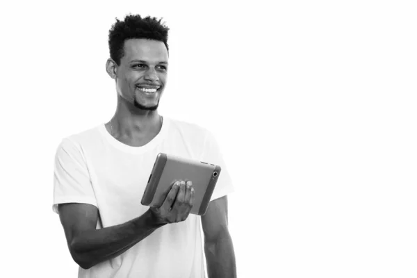 Dijital tablet tutarken gülümseyen düşünceli, genç, mutlu Afrikalı adam. — Stok fotoğraf