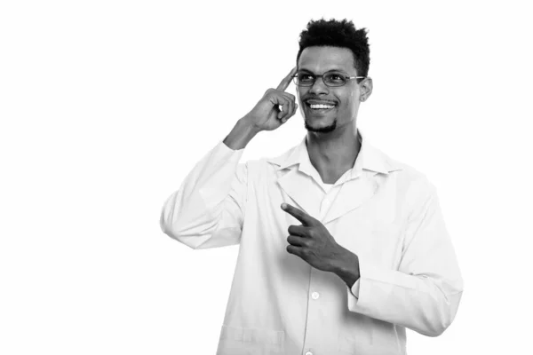 Young happy African man doctor smiling while thinking and pointing finger up — Stock Photo, Image