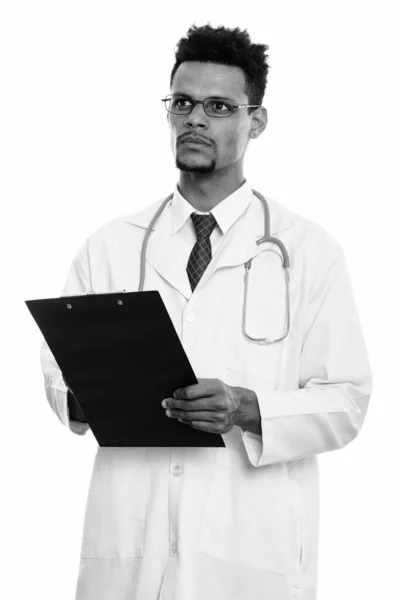 Captura de estudio de un joven médico africano sosteniendo el portapapeles mientras pensaba —  Fotos de Stock