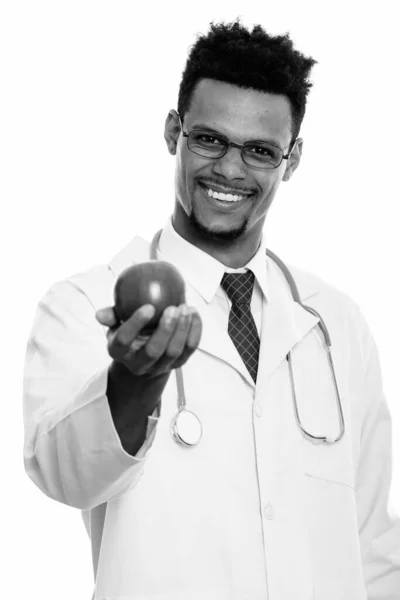 Студийный снимок молодого счастливого африканского врача, улыбающегося, давая яблоко — стоковое фото