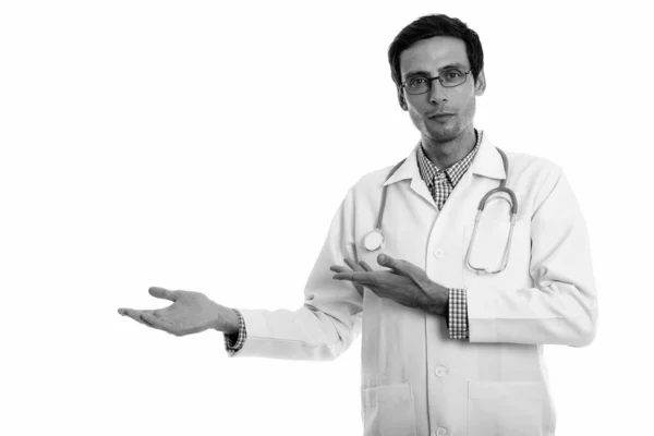 Studio shot of young handsome man doctor showing something — Stock Photo, Image