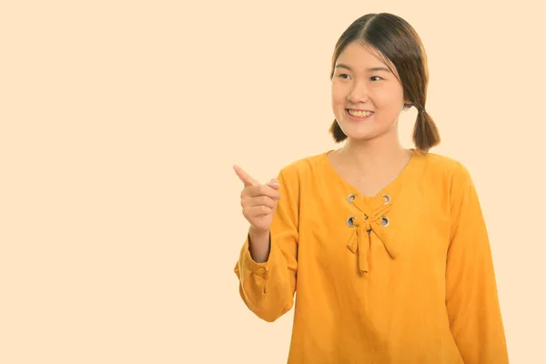 工作室拍摄的年轻快乐的亚洲女人一边微笑一边指指点点 — 图库照片