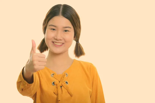 若いです幸せなアジアの女性のスタジオショット笑顔ながら親指をあきらめます — ストック写真